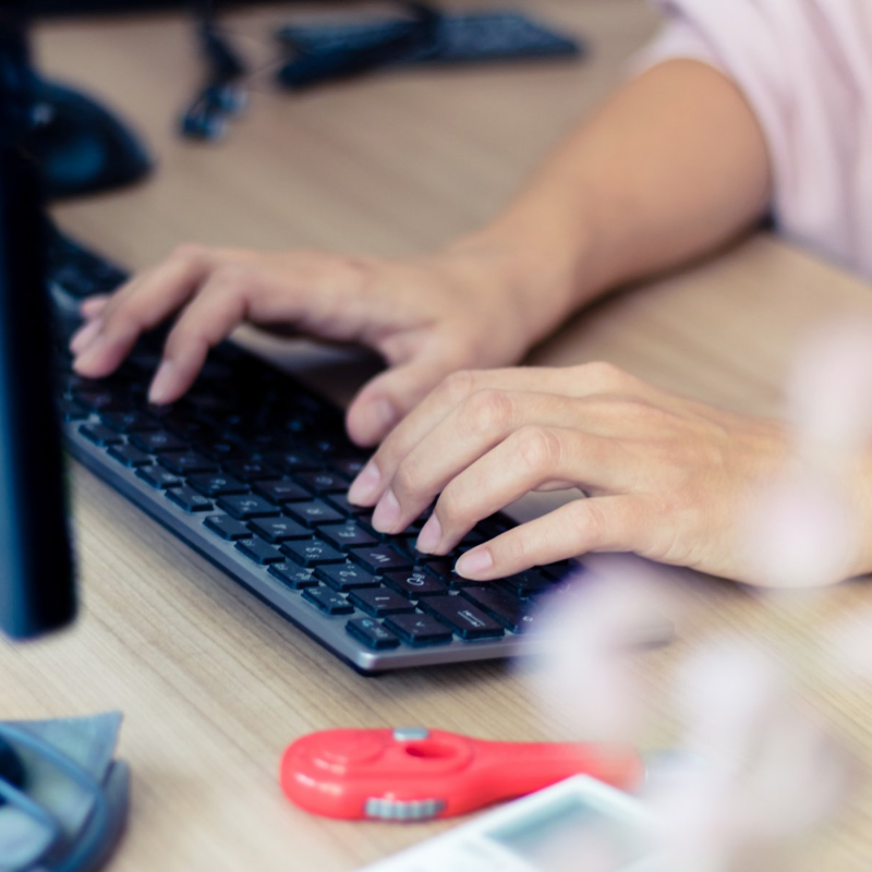 A close-up of a Scopists/Transcriber typing on a desktop computer keyboard.