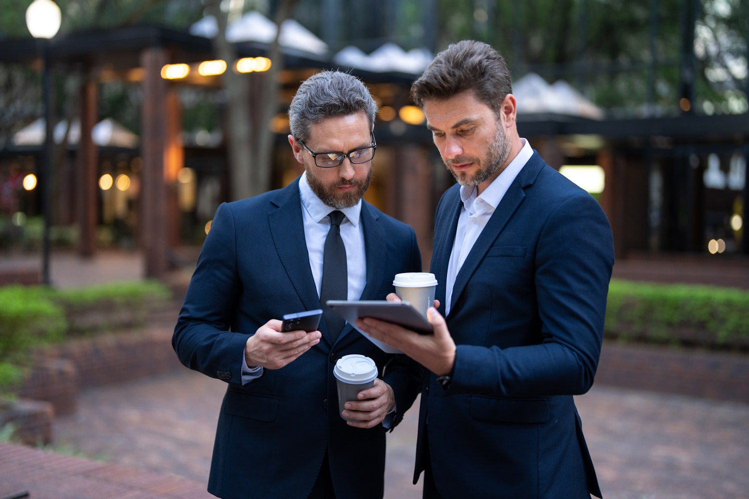 Two business men reading a tablet outdoors.